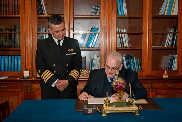 El capitán de Navío Carlos Zúñiga Araya observa al embajador dominicano Juan Cohen Sander firmar el libro de visitas.