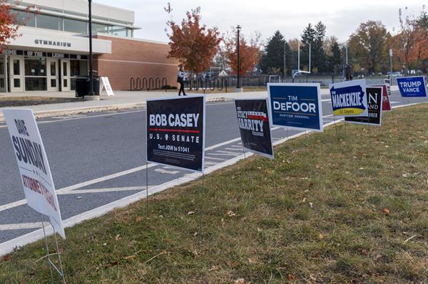 Una persona camina junto a carteles de los candidatos presidenciales, los demócratas Harris y Walz y los republicanos Trump y Vance, en la entrada de un centro de votación instalado en el gimnasio de la Escuela Secundaria Nitschmann, este martes, en Bethlehem, Pensilvania (Estados Unidos). EFE/Ángel Colmenares