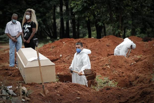 Un trabajador entierra a una víctima de covid-19, mientras familiares se lamentan en el Cementerio Vila Formosa, en Sao Paulo, Brasil.