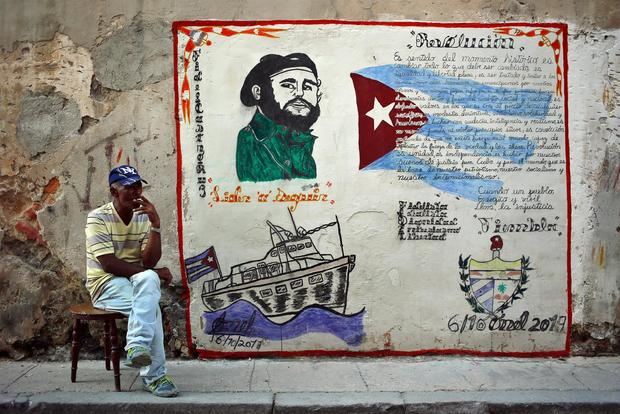 Fotografía de archivo en la que se registró a un hombre junto a un muro con la imagen de Fidel Castro, en La Habana, Cuba.