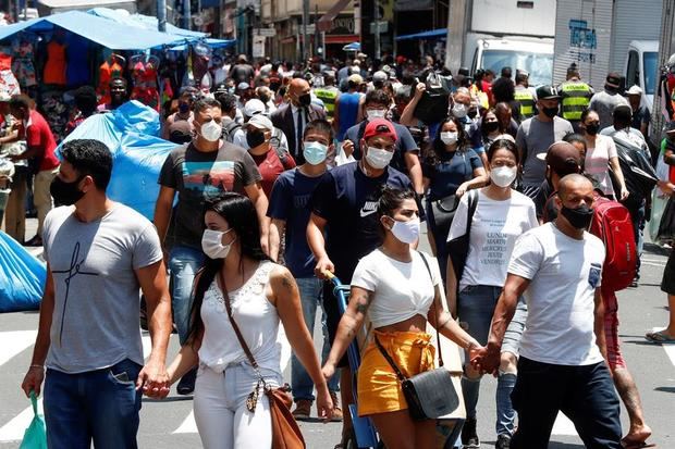 Decenas de personas caminan en una concurrida vía comercial en el centro de Sao Paulo, Brasil.