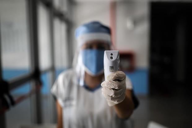 Una enfermera con tapabocas y protector toma la temperatura este jueves a quienes ingresan al Hospital El Cruce, en la localidad de Florencio Varela, en Buenos Aires, Argentina.