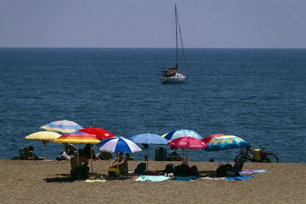 Bañistas bajo las sombrillas en la playa de La Malagueta de la capital de la Costa del Sol.