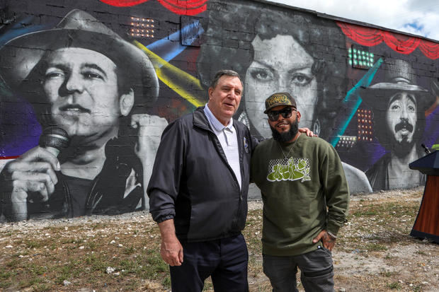 El artista venezolano Pedro Aguiar (d), conocido en el ambiente artístico como CYST1, posa frente a su mural acompañado por el comisionado de Miami para el Distrito 3 Joe Carollo.