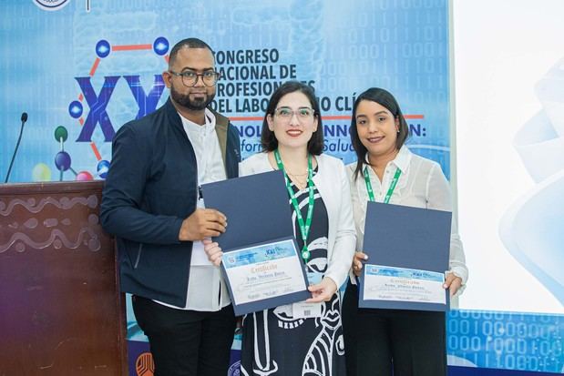 Verónica Porras y Noelia Parra reciben certificado de manos del vicepresidente del Colegio Dominicano de Bioanalistas (CODOBIO), Melvis Nicolás Mata.