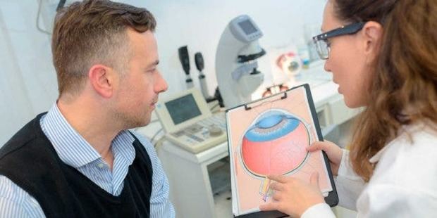 Una oftalmóloga le explica a un paciente cómo actúa el ojo.