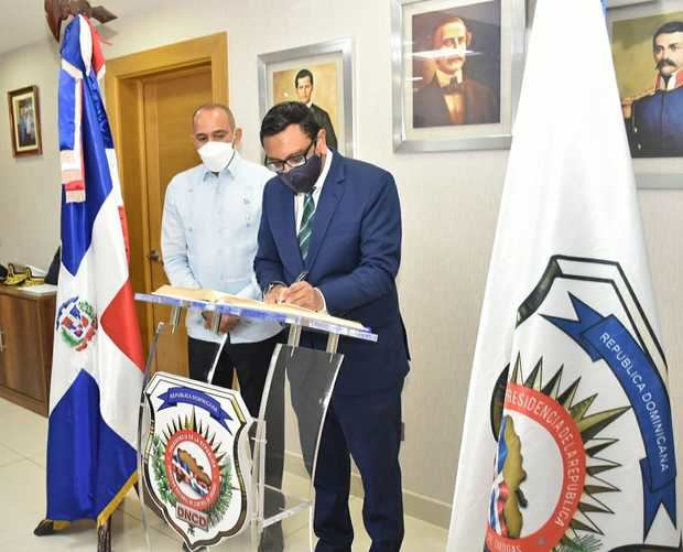 El embajador del Reino Unido Mockbul Ali OBE, firma el libro de personalidades durante su visita a la DNCD.