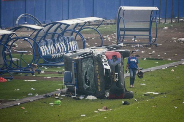 Una mujer camina junto a varios vehículos en el estadio Kanjuruhan, en la isla de Java.