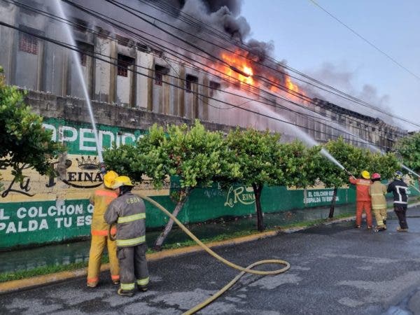 Bomberos tratan de sofocar incendio en una colchonerí­a en la capital.