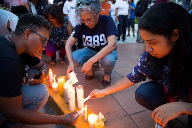 Manifestantes mientras encienden velas en señal de protesta.