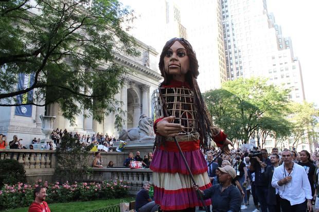 Cientos de personas reciben a la marioneta Amal, que en árabe significa esperanza, durante su marcha por las calles en el marco de la iniciativa 'The Walk' (El camino), lanzado por la compañía de teatro Good Chance, hoy, en Nueva York, EE.UU.