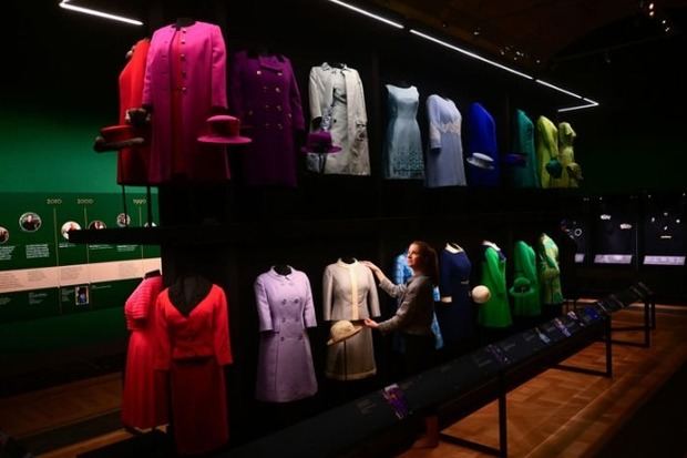 La conservadora textil Cecilia Oliver revisa los conjuntos de vestido y abrigo.