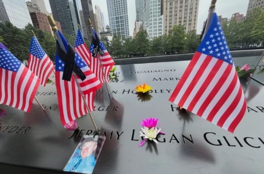 Banderas y flores se colocan en los nombres inscritos en el Monumento Nacional del 11 de Septiembre en Nueva York.