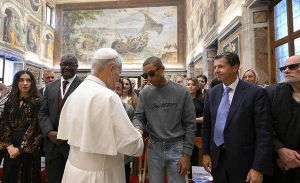 El papa León XIV saluda al cantante estadounidense Pharrell Williams (3d) en el Vaticano, un día antes de un concierto en la Plaza de San Pedro.