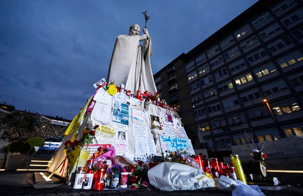 Flores, mensajes y velas al pie de la estatua de Juan Pablo II a la entrada del hospital Gemelli de Roma, donde el papa Francisco siguem ingresado por neumonía.