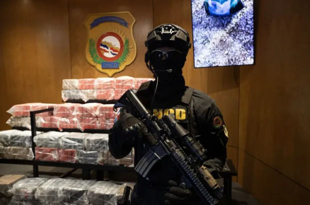 Un integrante de la Dirección Nacional de Control de Drogas (DNCD) custodia este domingo, 377 paquetes de la presunta cocaína que iba a bordo de la más reciente embarcación bombardeada por el Ejército de Estados Unidos en aguas del mar Caribe.