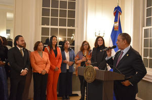 Congresista de Nueva York Adriano Espaillat dando discurso de bienvenida. La de la chaqueta naranja es la gobernadora Sabina Matos de Rhode Island, La de la chaqueta azul es Joseline Peña-Melnyk speaker of the house de Maryland.